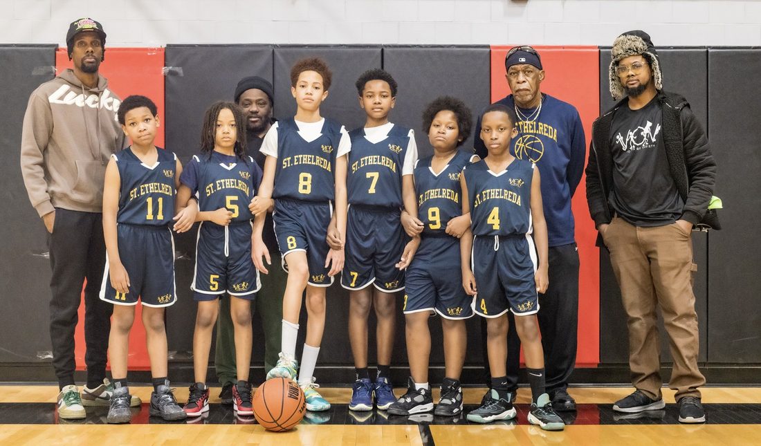 The St. Ethelreda V.O.V basketball team with their coaches in the gym