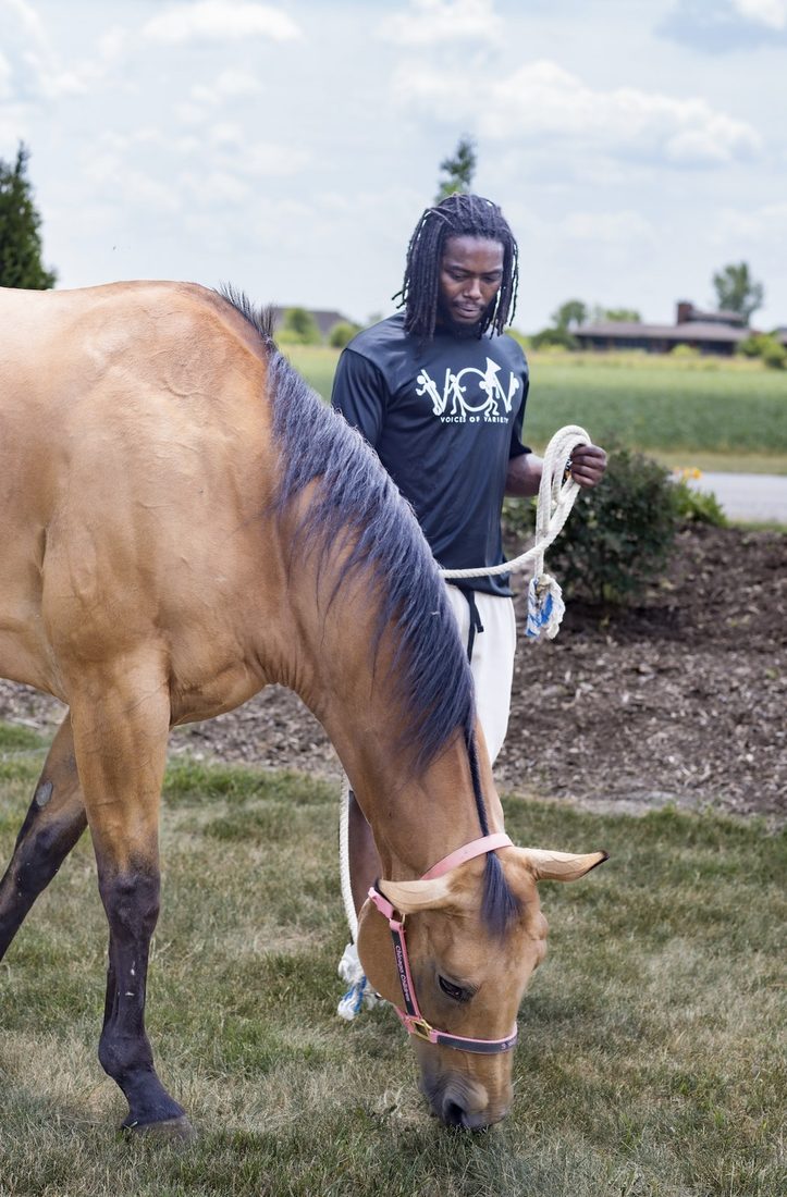 A V.O.V member leading a horse in an open field
