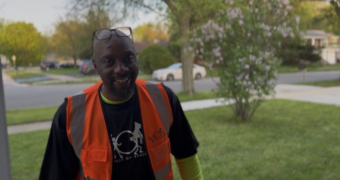 A smiling V.O.V crew member in an orange safety vest