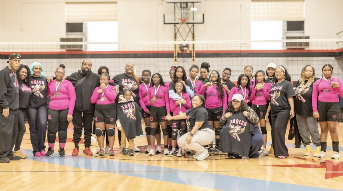 The V.O.V Eagles volleyball team and their families with medals in the gym