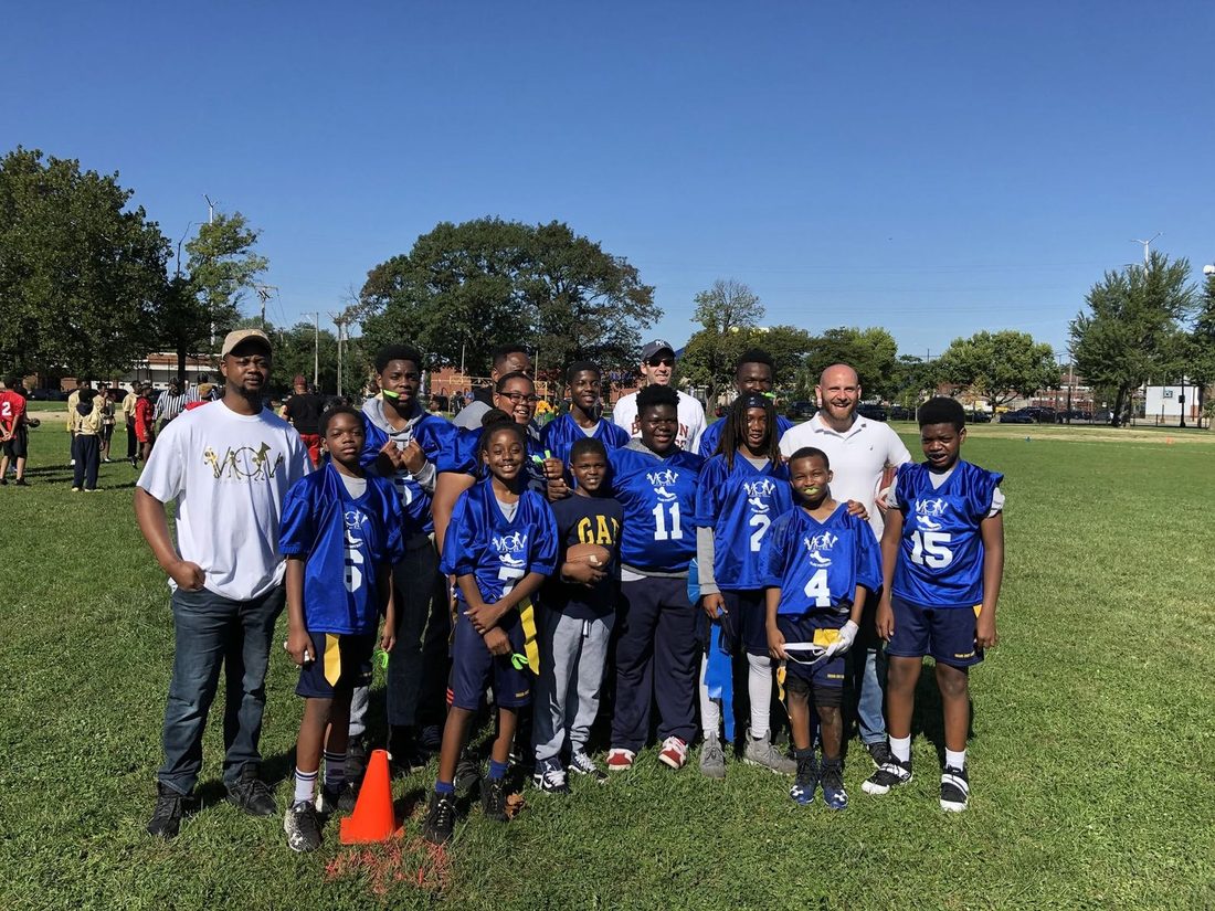 The V.O.V flag football team in blue jerseys with their coaches