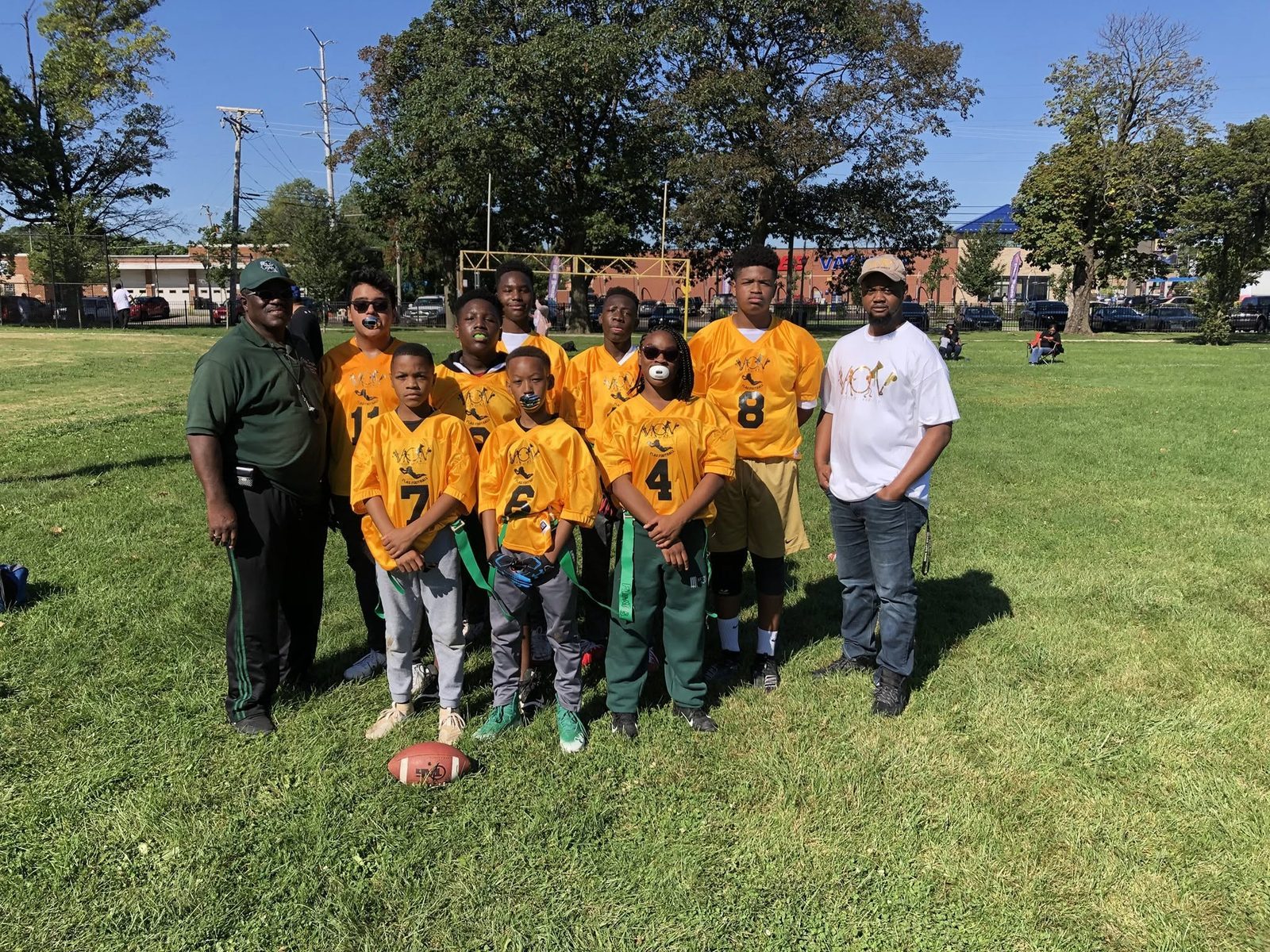 V.O.V flag football team in gold jerseys with their coaches