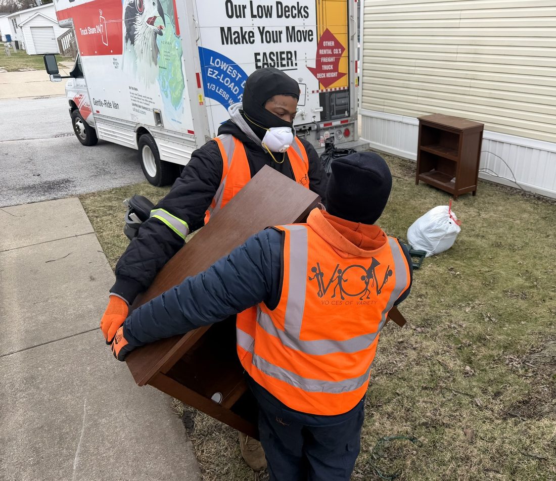Two V.O.V crew members carrying furniture during a community move