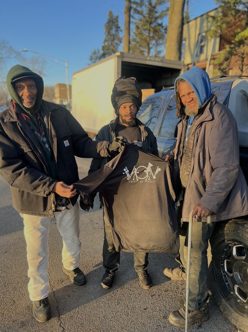 V.O.V outreach handing a shirt to neighbors on the block