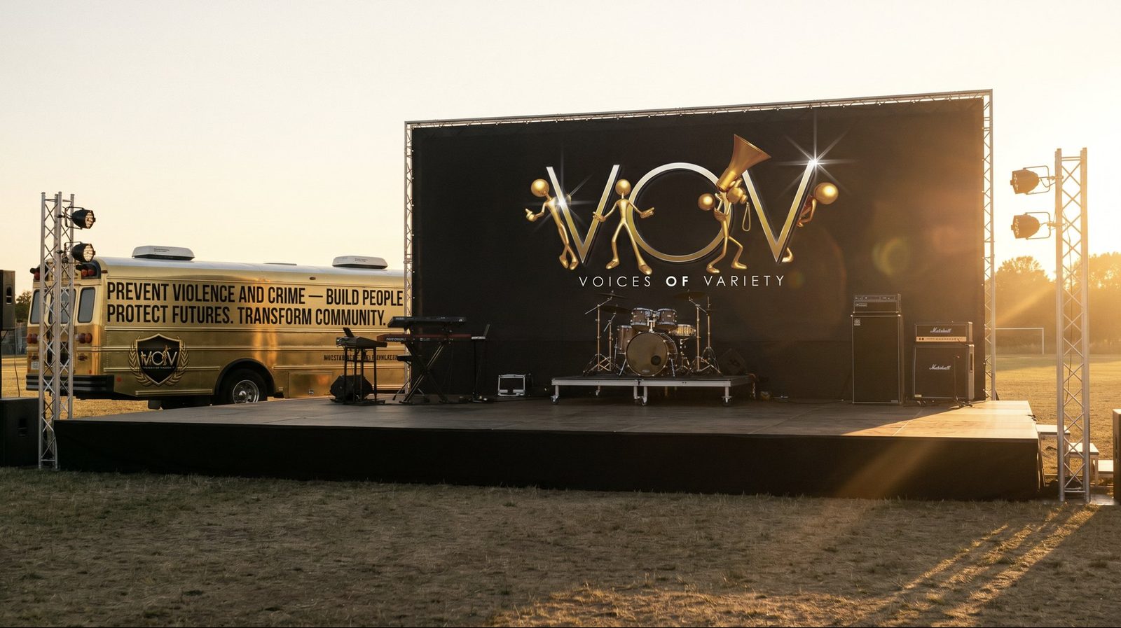 The V.O.V main stage at golden hour — drums and amps ready beneath the giant V.O.V backdrop, beside the gold V.O.V bus reading Prevent Violence and Crime, Build People, Protect Futures, Transform Community