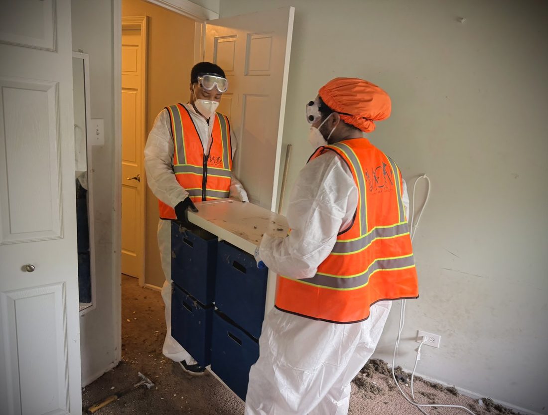 Two V.O.V crew members in safety gear carrying a cabinet