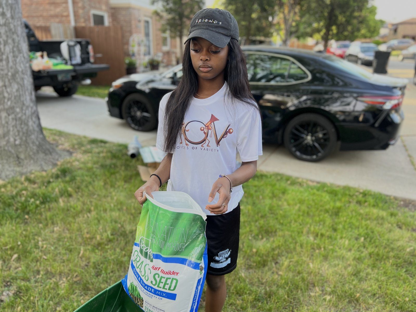 A V.O.V youth spreading grass seed on a lawn