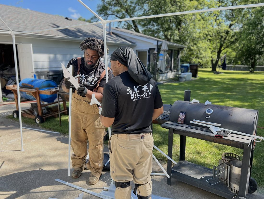 Two V.O.V members assembling a canopy frame for a cookout