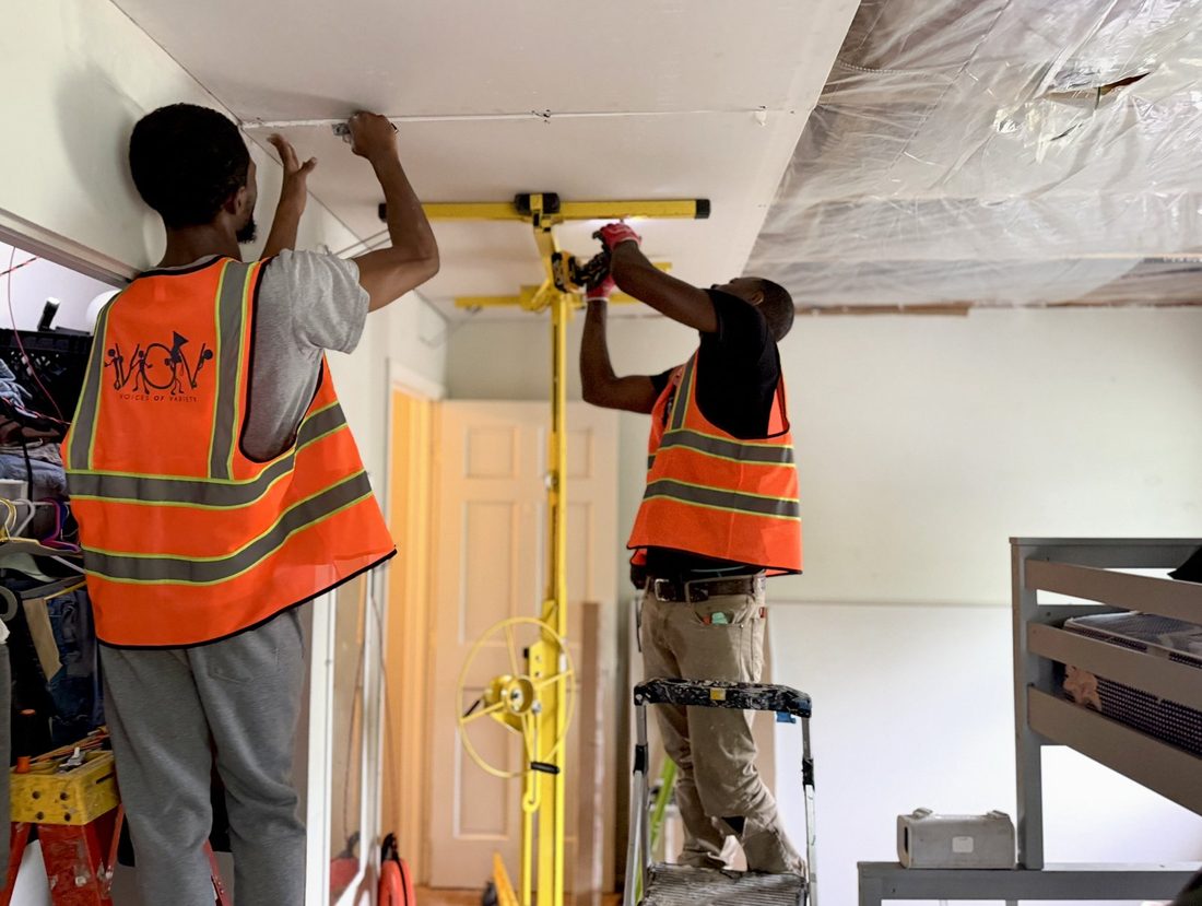 Two V.O.V workers installing a ceiling with a drywall lift