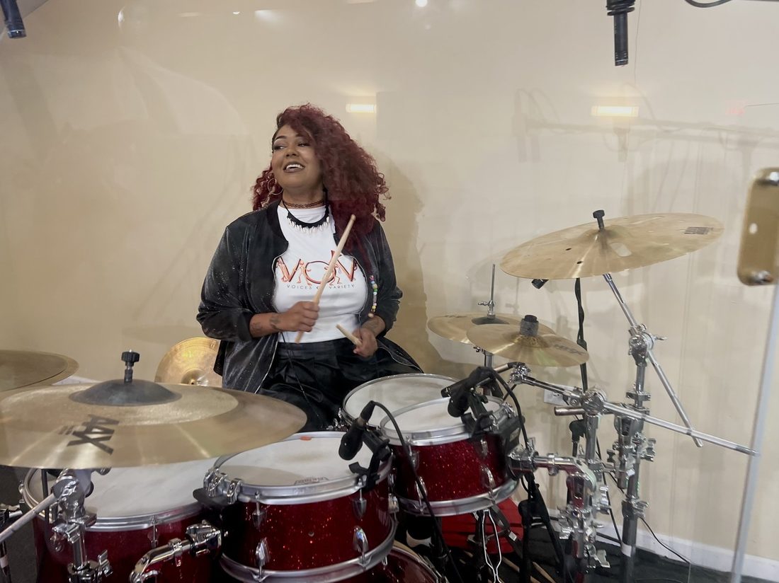 A V.O.V drummer smiling behind a red drum kit