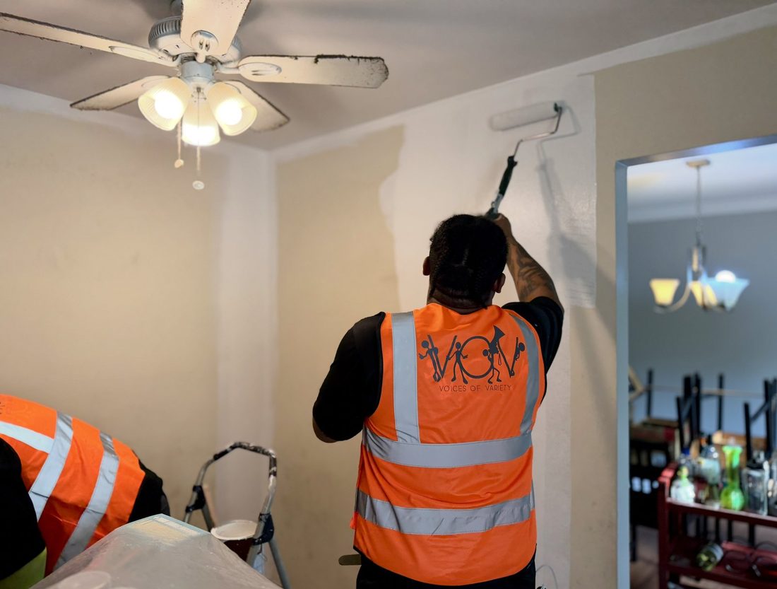 A V.O.V member rolling fresh paint onto a wall
