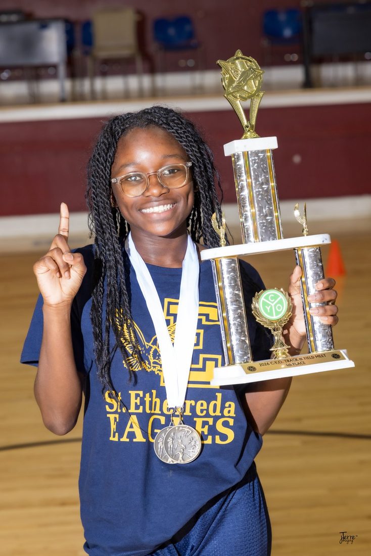 A young champion holding her 2026 track and field trophy and medals
