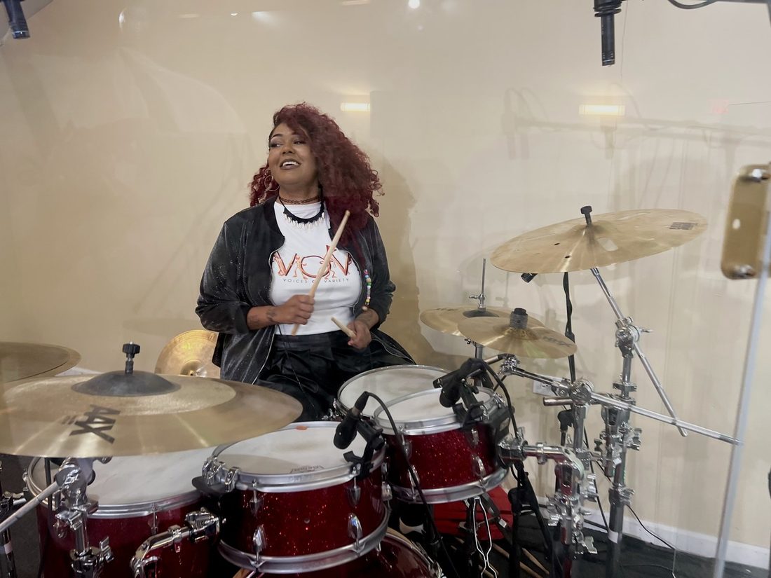 A V.O.V drummer behind a red drum kit in the studio
